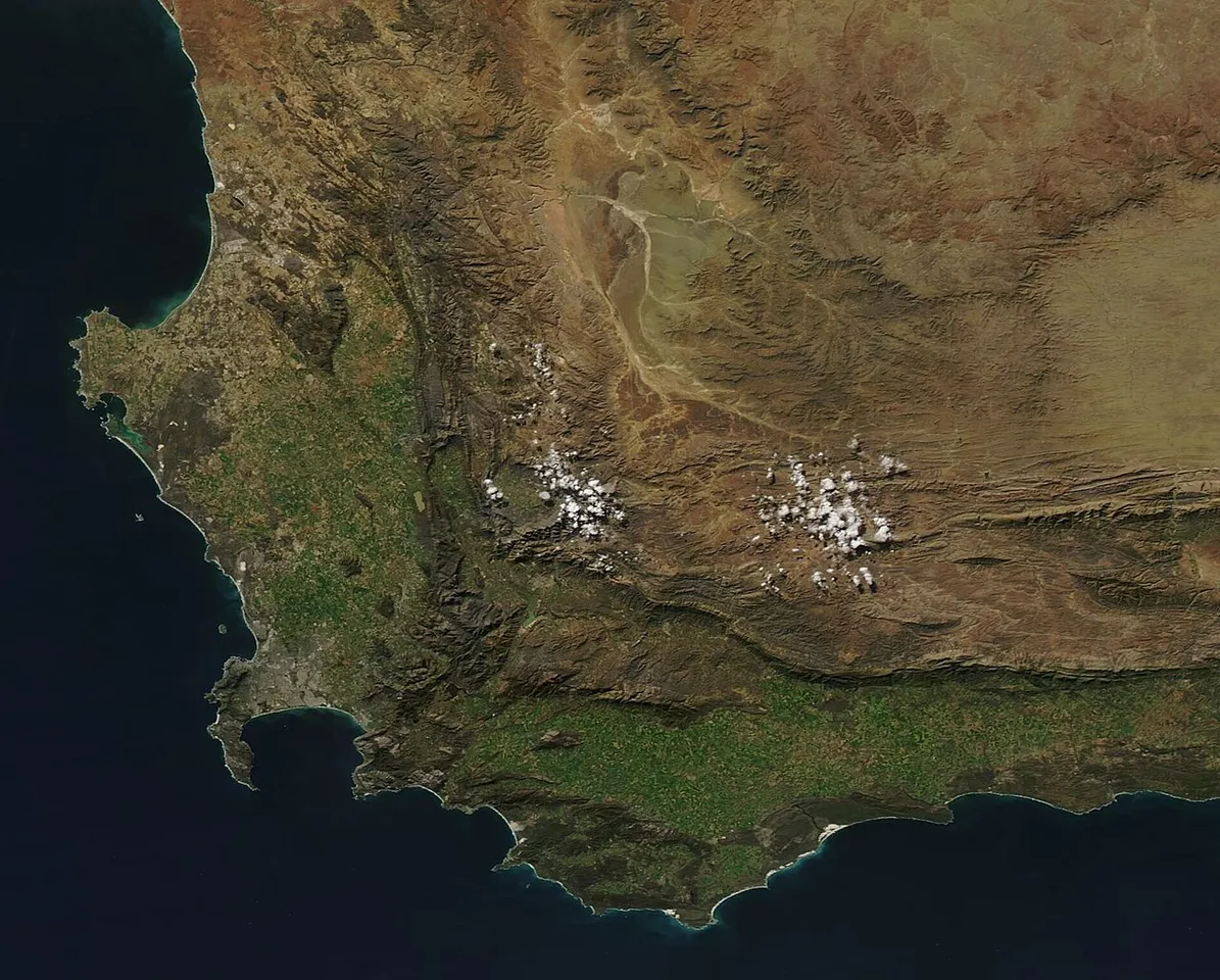 On July 28, 2022, the Moderate Resolution Imaging Spectroradiometer (MODIS) on board NASA’s Aqua satellite acquired a true-color image of a sunny mid-winter day on the southern tip of South Africa. Clear skies, punctuated only by a few clusters of cloud over high mountain peaks, allowed a detailed view of the diverse topography of the Western Cape region, all set against the dark waters of the South Pacific Ocean (west) and Indian Ocean (east). The finger-like projection off the southwestern coa